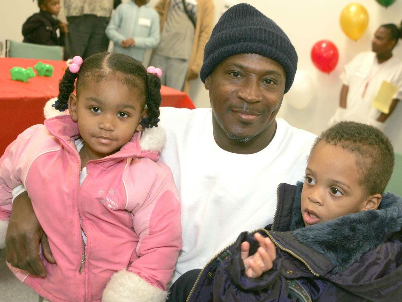A father holding his two young children at a FreshMinistries family event.